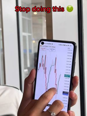 A person is holding a phone displaying a stock chart. The phone is black, and the screen shows red and green lines with price data. A finger is touching the screen. Above the phone, text overlays in red and with a light green emoji.