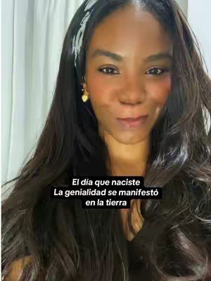 The cover image shows a woman in a selfie format. She appears to be indoors in a well-lit space. She has long, dark hair, a white headband with a floral pattern, and heart-shaped earrings. The background appears to be a white curtain or similar fabric. There is overlay text in Spanish at the bottom. She looks at the camera with a slight smile.