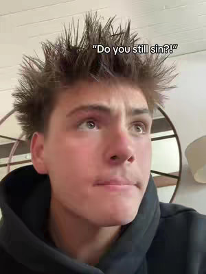 A young man with styled hair is featured in a medium close-up. He is wearing a black hooded sweatshirt and appears to be indoors. The background is a blurred interior with neutral tones. Text overlayed on the image says "Do you still sin?!"