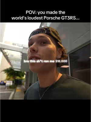A man in a black cap and dark t-shirt stands with a street setting as background. Text overlays indicate what appears to be a first-person perspective. The text mentions a costly exhaust component.