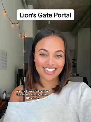A woman with fair skin and dark hair smiles at the camera.Text over her head says 'Lion's Gate Portal'.In the bottom left the text says 'and the Lion's Gate portal falls on the 8th day of the 8th month'.