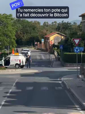 An outdoor scene featuring a road intersection with a bridge in the background. A blue rectangular text overlay reads: 'POV: Tu remercies ton pote qui t'a fait découvrir le Bitcoin'. A white van is parked on the left side of the image, and several cars are on the road. Green trees and foliage frame the background scene.
