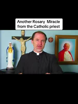 A middle-aged man in a priestly collar stands in front of a blue wall. Behind him are a crucifix with a gold Jesus figure, a statue of the Virgin Mary, and a framed picture of a religious figure. The man is the central focus, addressing the camera. A banner at the top reads, “Another Rosary Miracle from the Catholic priest”.