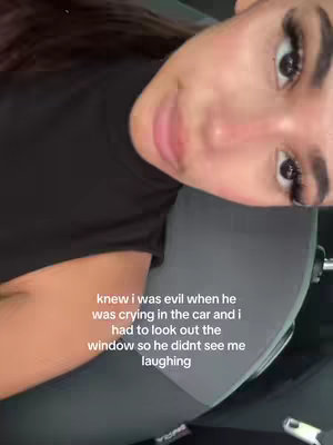 A woman with long dark hair is shown in close up from the chest up inside a car. The lighting is well-lit, with warm tones. The woman is looking at the camera at a slightly downward angle. The text overlay is white.