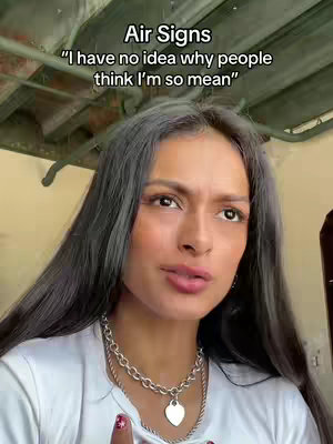 A medium shot features a woman with long, dark hair. She's wearing a white shirt and a layered silver necklace with a heart pendant. Text overlayed on the top reads "Air Signs" and a quote. The background is slightly out of focus.