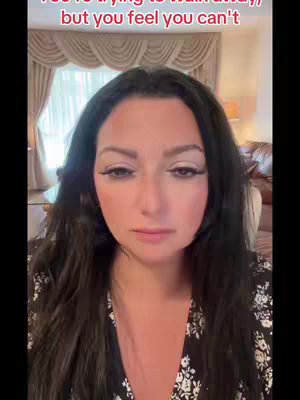 A woman with long dark hair, wearing a black floral top, stares directly at the camera with a somber expression. Text overlays are present at the top portion of the image.
