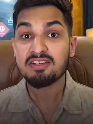 A close-up shot of a man with a beard and open mouth, possibly talking. The background is blurred.