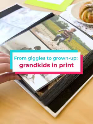 A person's hand opens a photo album filled with photos. On top of the album is a text overlay against the image of the photos. The background shows a table with a plate of food.