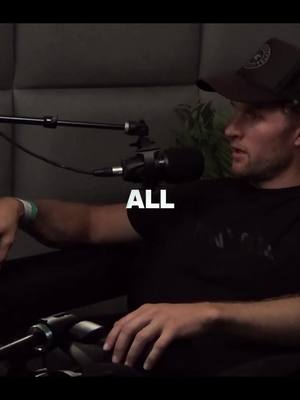 The image shows a man in a black cap and black shirt sitting in a dark setting, likely a podcast studio. The word 'ALL' is overlaid in large white text. Microphones and audio equipment are visible. The image has a serious tone.