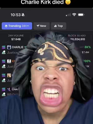 The cover image shows a close-up of a person's face, likely the creator of the video, making a distorted and exaggerated expression. They have their mouth wide open, showing their teeth, and their eyes are wide with rolled pupils. The person is wearing a black head covering with a gold patterned design. The background shows a phone screen with a news feed or social media interface, displaying text and data, including some financial information. The overall color scheme is dark with the skin color being a warmer shade.