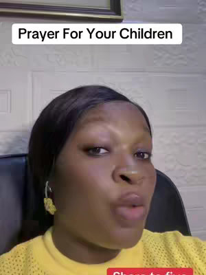 A woman with dark skin is the focus of the selfie-style video, captured from the chest up. She is centered in the shot, wearing a yellow patterned top and gold-colored hoop earrings. The background is light-toned with a textured pattern, and a framed picture hangs behind her. The text 'Prayer For Your Children' appears in a white box above her head, and a small, red 'Share to five' message is visible in the bottom right corner. Her expression shows that she is speaking.