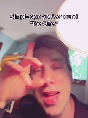 A man looking directly at the camera, making the "okay" hand gesture with his left hand. Text overlayed on the top.
