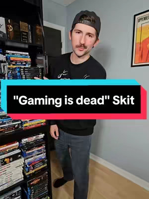 A man with a mustache and a backward baseball cap stands in front of bookshelves filled with DVDs and Blu-rays. A large rectangular text overlay reads, "'Gaming is dead' Skit". The man wears a black t-shirt and jeans. A framed artwork is visible on the wall to the right.