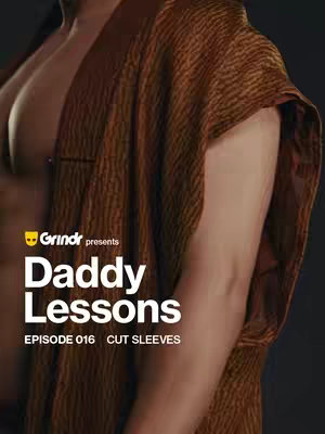 The image is a close-up shot of a man's upper body. He is partially undressed, with his chest and one arm exposed. He is wearing a draped garment, potentially a robe or wrap, in a striated brown and beige pattern. The background is a neutral dark color.
On the bottom left of the image, there is a logo in the shape of a yellow face with a white backdrop and the name \"Grindr presents\". The text \": Daddy Lessons:\" is overlayed in a bold, white font with a black outline. Underneath the text \"Daddy Lessons\" is the text \"EPISODE 016 CUT SLEEVES\".
