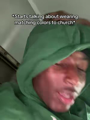 A close-up selfie features a Black man's face, with eyes closed and a slight smile, wearing a green hoodie with the hood up. Text overlay appears at the top, giving context.