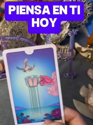 The cover image displays a tarot card held up in front of a background that includes other spiritual objects. The tarot card in focus depicts a cup being held up by a hand and a bird flying towards it, with a lake and mountains in the background. In the top center is a purple box overlay with white text that reads 'PIENSA EN TI HOY'.