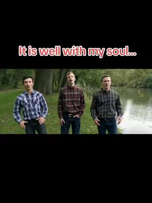 Three men standing in a grassy area beside a river, each wearing a plaid shirt and jeans. Text overlay at the top reads "It is well with my soul..."