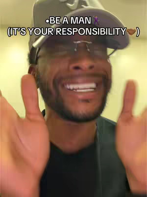 A close-up shot of a man wearing a baseball cap and glasses with a text overlay. The man is smiling, and his hands are outstretched towards the camera. The background is blurred and appears to be indoors with yellow lighting.