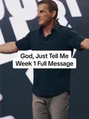 A man with short brown hair is centered, slightly angled to the left, with arms outstretched. He wears a dark blue shirt. White text is overlaid at the bottom, against a black backdrop.
