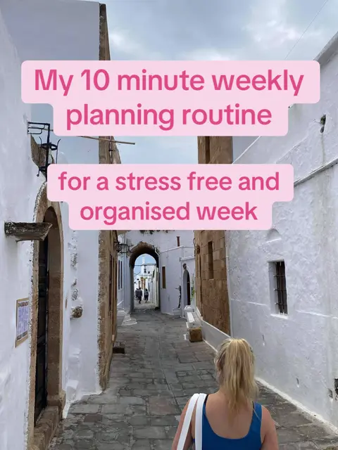 A shot from behind a woman walking down a narrow cobblestone street with white buildings and pink text overlays.
