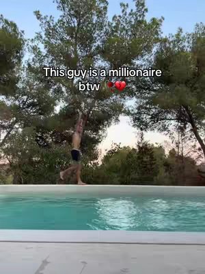 A man in swim trunks walks along the edge of an infinity pool, with a natural background of trees and sky. Text overlays the image, and a heart symbol is also present.