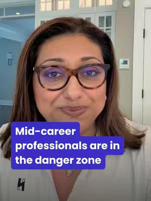 A woman with brown hair and glasses looks directly at the camera. A text overlay, a blue rectangle, spans the lower portion of the frame, displaying the text. The background includes interior architectural elements, primarily white.