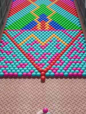 The cover image features a colorful arrangement of spheres, resembling a 3D rendering of a bubble-popping game. A large, complex pattern of colored spheres dominates the upper portion, arranged in distinct rows of red, green, blue, and yellow, forming a diamond-like shape. Below this, smaller rows of blue, pink, and red spheres meet at a point, and at the bottom, there is a single ball set in a metal textured environment.