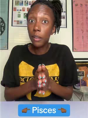 A person with dark skin, wearing a black t-shirt with yellow text logo, hands clasped in front of them, with a light blue rectangle below them that says "Pisces" with two finger-pointing right emojis flanking the message.