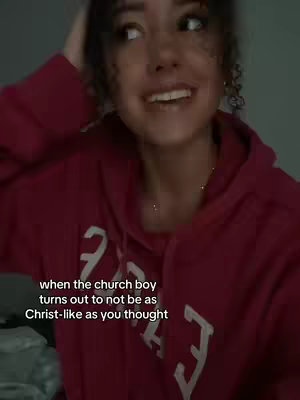 A young woman with curly hair smiles, looking off to the side. She wears a maroon hoodie, and the text overlay near the bottom of the image reads: "when the church boy turns out to not be as Christ-like as you thought". The background is a blurred, desaturated gray.