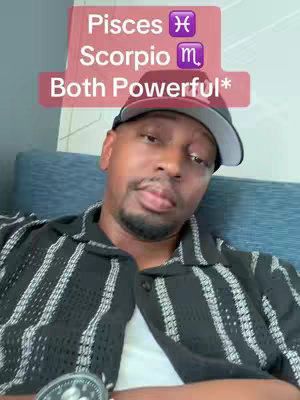 A man with a dark complexion is the main subject, wearing a black collared shirt with white vertical lining and a black baseball cap. Overlayed on the image is a pink rectangle with white text, identifying astrological signs: Pisces, Scorpio, and 'Both Powerful'. The background shows a blue couch, adding a touch of color to the image.