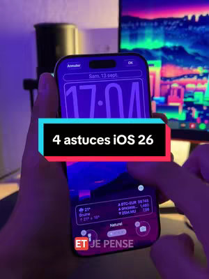 The cover image features a person holding an iPhone displaying the iOS 26 interface. The screen shows a clock widget set to 17:01 on Saturday, September 13th, along with weather and stock information. A black rectangle with white text overlay reads "4 astuces iOS 26". The background includes a microphone and a colorful computer screen, all illuminated with a purple hue.