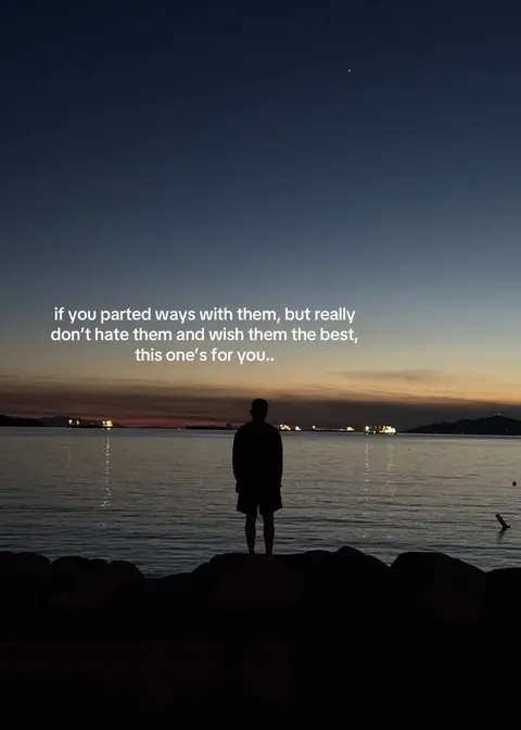 A silhouette of a person standing on a rocky shoreline, facing a body of water at dusk. The sky transitions from deep blue at the top to shades of orange and pink along the horizon, with some boats in the distance. Text overlayed on the image reads: "if you parted ways with them, but really don't hate them and wish them the best, this one's for you.."
