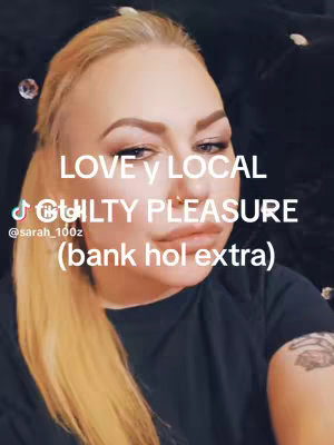 A selfie-style shot featuring a woman with blonde hair, facing the camera. She has visible makeup, a nose ring, and is wearing a black top. Text overlays provide context.