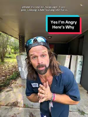 A man with long hair and a beard is standing on a porch. He's wearing a work shirt, sunglasses on a hat, and has a serious expression. The text overlays state, 'Yes I'm Angry Here's Why' and 'please excuse my language. I am just venting while stating the facts'.