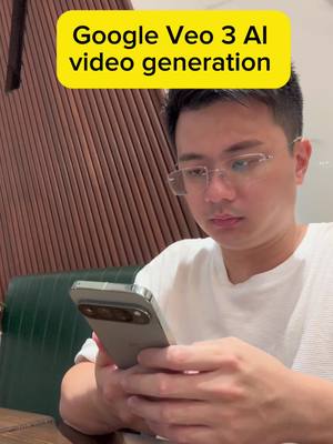 A selfie-style shot with a man looking down at a smartphone. He is wearing glasses and a white t-shirt. A yellow rectangular text overlay reads 'Google Veo 3 AI video generation'. The background shows a wood-paneled wall and a green bench.