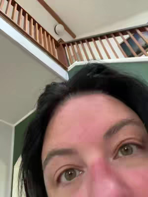 The cover image is a close-up shot of a person's face, occupying most of the frame. The person's eyes, nose, and a portion of the forehead are visible. The background slightly out of focus, showing a mix of wall and ceiling with a staircase.