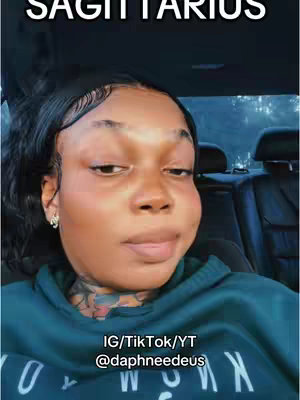 A woman in a teal hoodie sits in a car, looking at the camera with a neutral expression. The background suggests an interior setting. Text overlays the image naming the zodiac sign Sagittarius and social media handles.