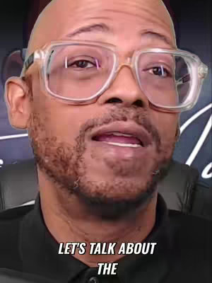 The cover image is a close-up of a man with a bald head and a neatly trimmed beard. He wears large, clear-framed glasses. The background is a blurred mix of colors. Text overlayed at the bottom says, 'LET'S TALK ABOUT THE.'