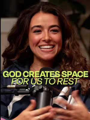 The cover image features a woman with long, wavy brown hair, smiling directly at the camera. She's wearing a dark blue and white jacket, and a microphone is positioned in front of her. The background appears to be a softly lit room. Text overlaid on the image reads 'GOD CREATES SPACE FOR US TO REST' in a yellow, sans-serif font.