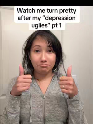 A woman with dark hair and a gray zip-up hoodie looks toward the camera with a slightly pursed mouth. Her eyebrows are raised and she is giving a thumbs up with both hands. Above her are the words "Watch me turn pretty after my 'depression uglies' pt 1". The background is a plain white.