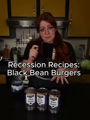 A woman in a kitchen setting points at the camera. Text overlays the bottom of the image. Three cans of black beans are placed in front of the creator.