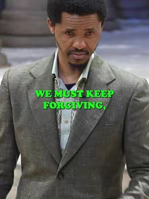 A medium shot of a man wearing a gray blazer and a light green shirt, looking towards the camera. The overlaid text reads, "WE MUST KEEP FORGIVING," in bright green font.