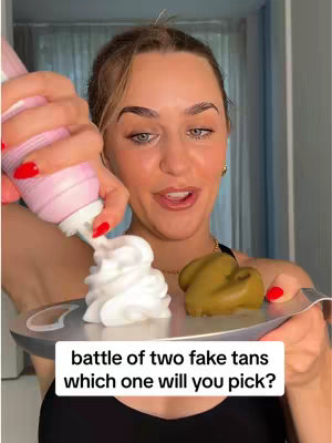 A woman holds a silver platter showcasing two fake tan products. A bottle of pink spray product is on the left is ready to spray a white mousse, and a brown product is on the right.