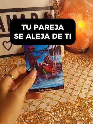 A hand holding a tarot card featuring a boat and two figures. Overlayed with a black banner containing white text. The background includes decorative elements and soft lighting.