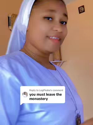 The cover image shows a young woman, presumably a nun, in a close-up shot. She is wearing a white habit. In the lower-left corner, a comment overlay displays the text "Reply to LogPkaha's comment you must leave the monastery". The background is a light tan color, and there are hints of interior details. The woman is smiling and looking to the side.