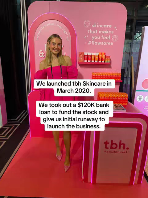 A woman in a pink dress stands in front of a pink and white display featuring skincare products, a product and brand launch setting. Text overlays convey key business milestones.