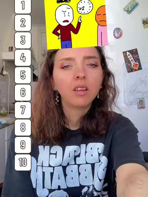 A young woman is centered in the frame, looking up with a slight frown. Above her head is a small yellow rectangle that features a cartoon drawing of three figures: a stick figure with a concerned expression, a clock, and another stick figure. The background includes a kitchen setting and various items on the wall.