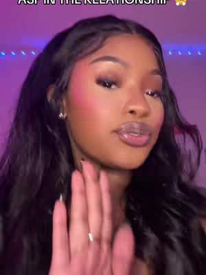 A close-up shot of a woman with long, dark hair, wearing makeup, and gesturing with her hand. The background is a soft purple, and the overall composition has a modern, social media feel.