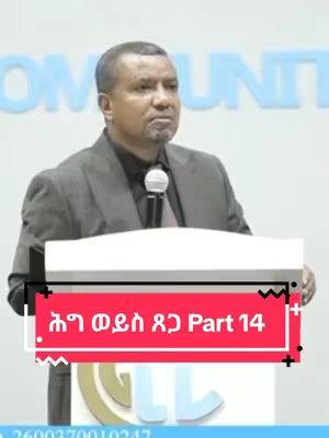 A man in a suit stands behind a podium with a microphone in hand, presenting to an audience. A red banner with white text is placed at the bottom of the image.
