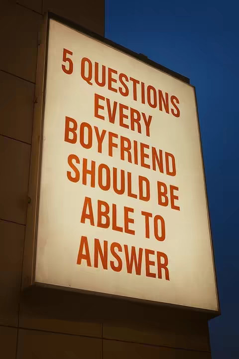 Image features a brightly lit sign with text against a dark blue background. The sign is rectangular, with a slightly beveled edge, and the text is aligned in a vertical stack. The text is large, bold, and red, against the illuminated, off-white background of the sign. A wall is visible to the left, adding depth and context to the scene.